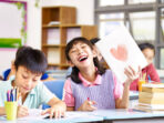 happy and lovely asian elementary school girl showing a drawing and laughing.