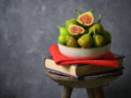 Ripe figs heap on book and old wooden stool in studio